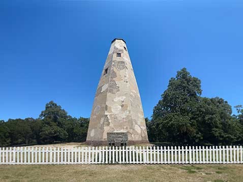 Stone tower behind a white picket fence